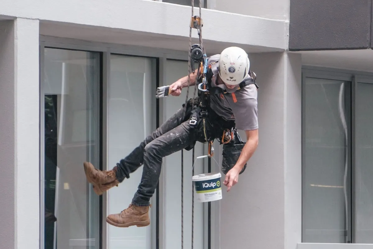 contractor painting building using rope access